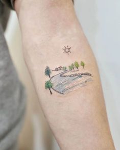 a woman's arm with a small watercolor landscape tattoo on the left forearm