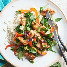 a white plate topped with chicken and veggies next to rice on top of a table