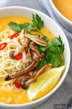 a white bowl filled with noodles, mushrooms and garnished with cilantro