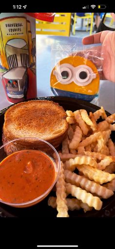 a sandwich and french fries on a black plate with an eye - shaped object in the background