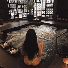 a woman in a yellow bathing suit sitting on the edge of an indoor hot tub