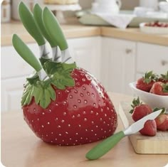 strawberries are being cut in half on a cutting board next to a bowl of strawberries