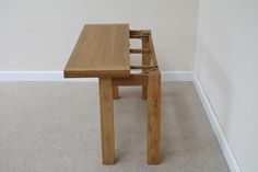 a wooden table sitting on top of a carpeted floor next to a white wall