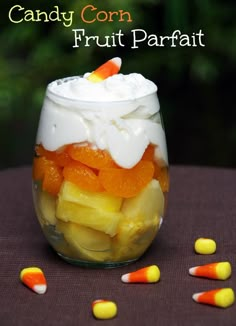 candy corn fruit parfait in a glass jar with marshmallows on the side