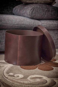 a brown leather bag sitting on top of a rug next to a couch and pillows