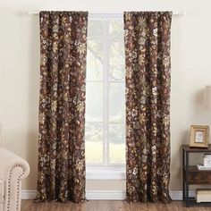 a living room with a couch, chair and window covered in floral print curtain panels