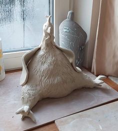 a ceramic bird sitting on top of a table next to a window