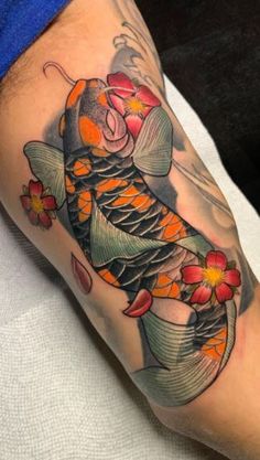 a person with a tattoo on their arm has a fish and flowers on his leg