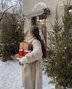 a woman is carrying presents in the snow