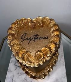 a gold heart shaped box with the word saffroni written on it in cursive writing