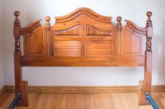 a wooden bed frame sitting on top of a hard wood floor next to a wall