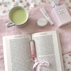 an open book with a pink ribbon on it next to a cup of coffee and other items