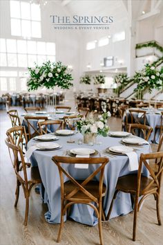 the springs wedding and event venue is set up with blue linens, wooden chairs, and white flowers