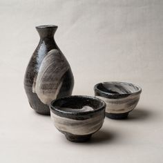 three black and white vases sitting next to each other