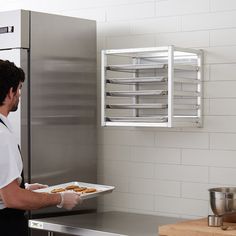 a man holding a tray of food in front of an oven