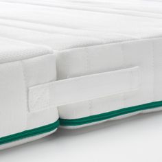 the side of a white mattress with green piping