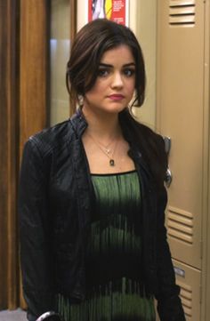 a woman standing in front of a locker with her hand on her hip and looking at the camera