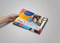 a person holding up a colorful brochure in their hand, with the image of two people on it