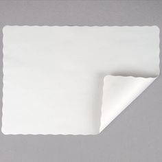 an empty white napkin folded on top of a gray surface with a corner cut out