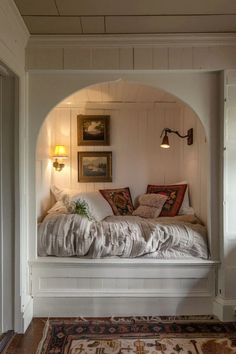 a white bed sitting under a window next to a rug