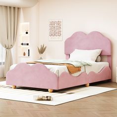 a pink bed sitting on top of a hard wood floor next to a white rug