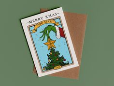 a merry xmas card with a christmas tree and star on the front, sitting on top of a brown envelope