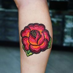 a woman's leg with a rose tattoo on the lower half of her arm