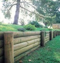 a wooden fence in the middle of a grassy area with trees and grass on top