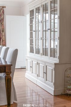 the dining room table is set with white chairs and china cabinet in front of it