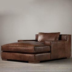 a large brown leather chaise lounge chair in a room with hardwood floors and white walls