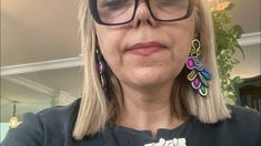 a woman with glasses wearing some colorful earrings