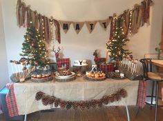 a table topped with lots of desserts and christmas trees in front of a wall