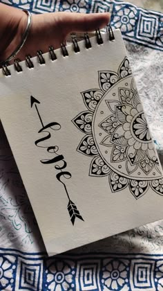 a hand holding a spiral notebook with an arrow on it and the word hope written in cursive writing