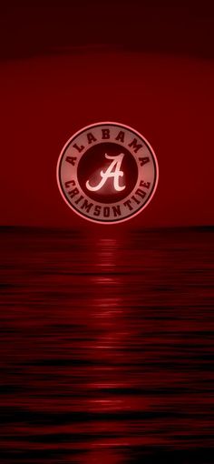 the university of alabama logo is lit up at night over the water with red hues