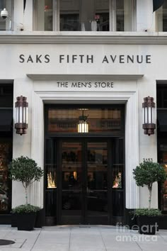 an entrance to a men's store with potted plants