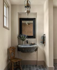 a bathroom with a sink, mirror and wooden chair in the corner next to it