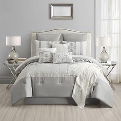 a white and grey bed with pillows and blankets