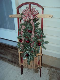 a wooden sled with a christmas tree in it and decorations on the front door