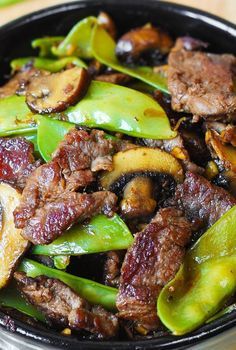 beef and mushrooms stir - fry in a wok with green peppers on the side