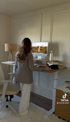 a woman standing in front of a desk with a computer on it