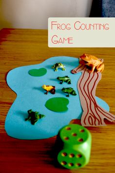 a frog counting game is shown on a wooden table with dices and other items