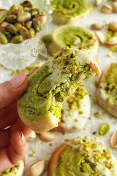 a person is holding up a pastry with pistachio and almonds on it