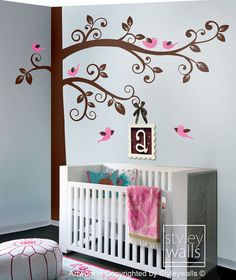 a baby's room decorated with pink and brown birds on a tree wall decal