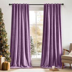 a living room with a christmas tree and purple curtains