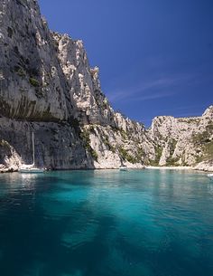 there is a boat that is in the water near some rocks and cliffs on the shore