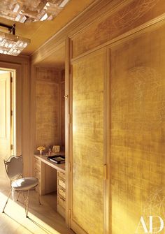 a chair and desk in a room with wood paneling on the walls, along with an open closet door