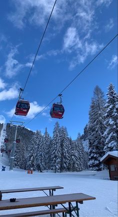 the ski lift is going over the snow covered mountains and trees, with benches underneath it