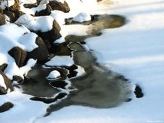 snow covered rocks and water running through them