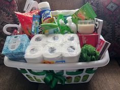 a white basket filled with lots of toilet paper and other items on top of a couch