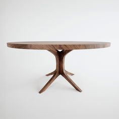 an oval wooden table with two crossed legs and a circular shaped top, against a white background